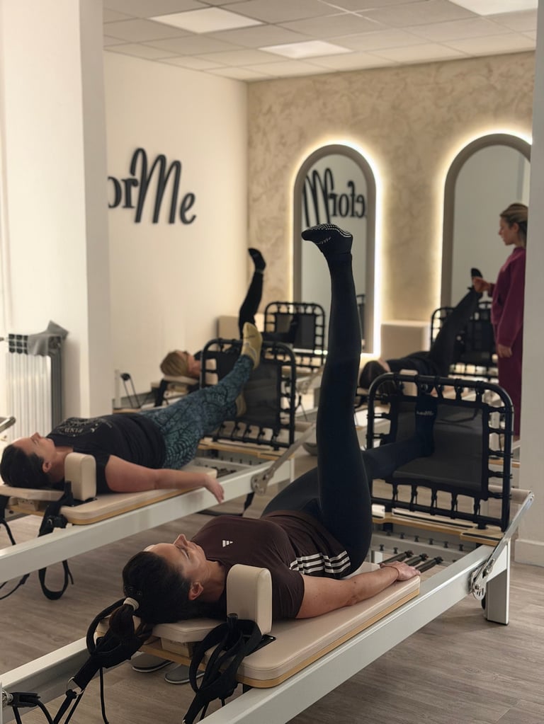 People performing Pilates reformer exercises in a studio with arched mirror alcoves and instructors observing