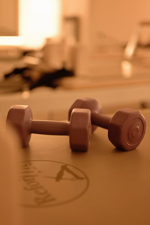 Pair of red dumbbells on a wooden floor in a home gym setting